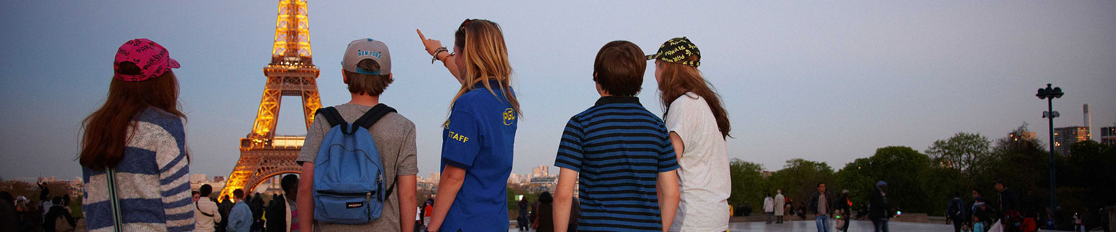 A group of children being shown the Eiffel Tower lit up at night